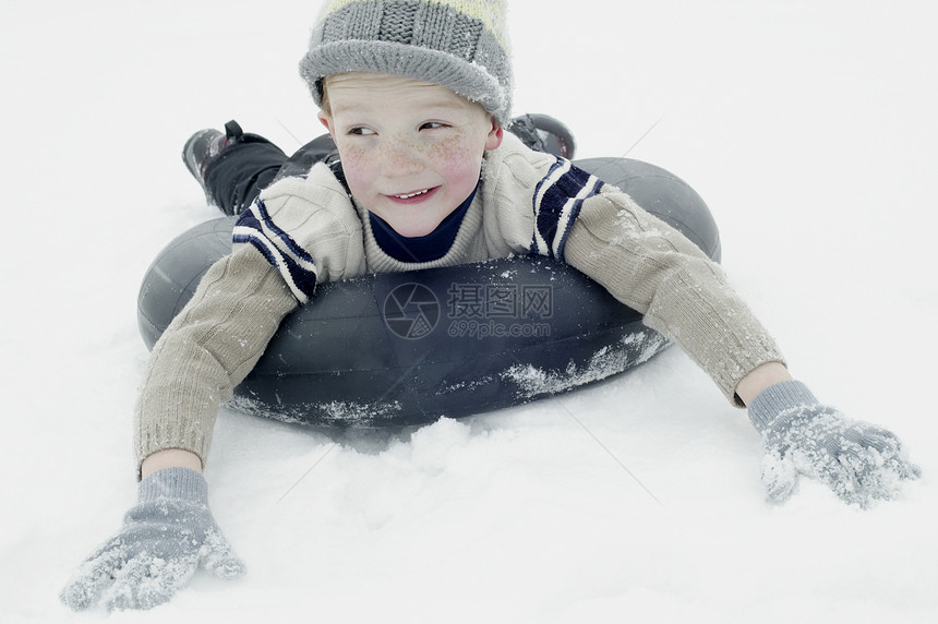 身着冬衣的男孩在车内轮胎上滑雪图片