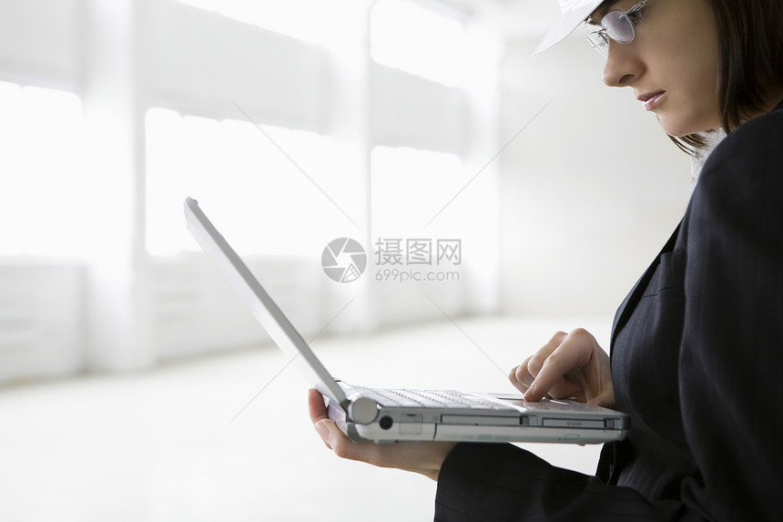 在空仓库从事膝上型电脑工作的商业妇女图片