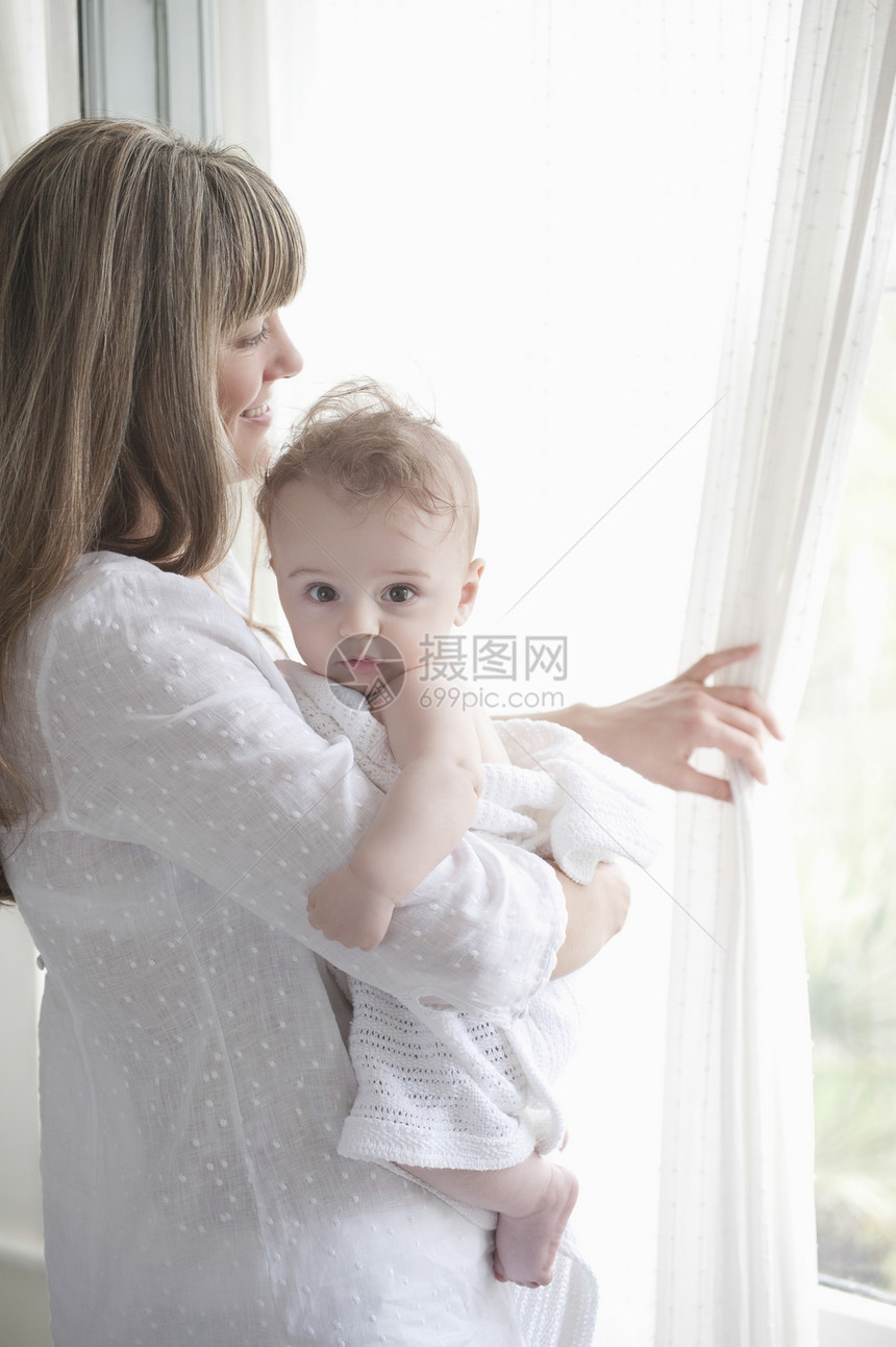 母亲站在窗边看着一个小男孩 却抱着一个小男孩图片