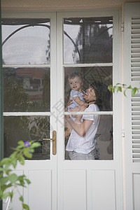 法式门素材母亲和幼儿儿童站在玻璃窗的门内背景