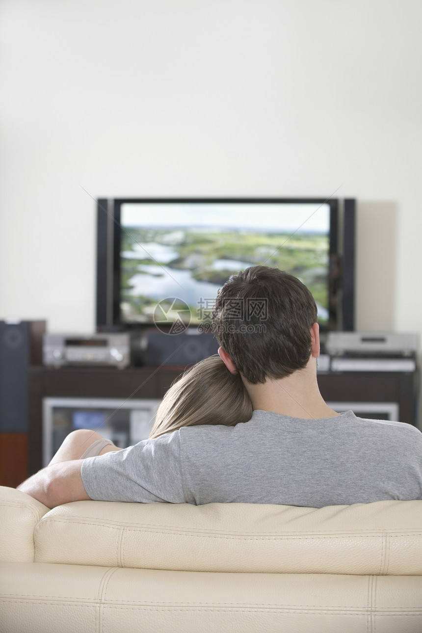 年轻夫妇坐在电视上看电视图片