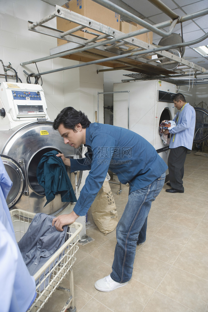 男人把衣服装进洗衣机中裁缝烘干机商业衣物家族企业职业衣架成人工作图片