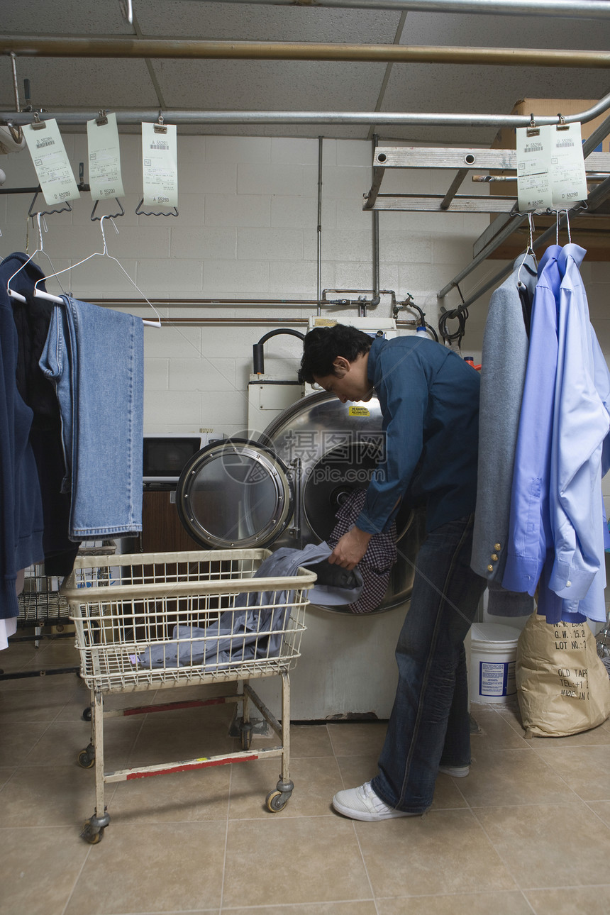 男人把衣服装进洗衣机中企业衣架男性家族打扫干洗店成人裁缝商业工作图片