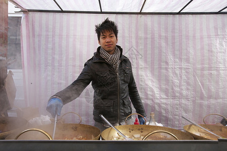 小本经营街边摊一名亚洲青年男子在街头食品摊做饭的肖像背景