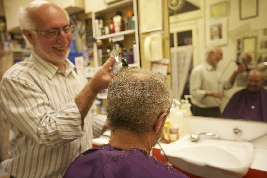 快乐男人用剃刀剪高级顾客的头发图片