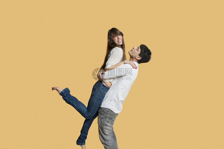 快乐的年轻男人带着女朋友 背着彩色背景图片