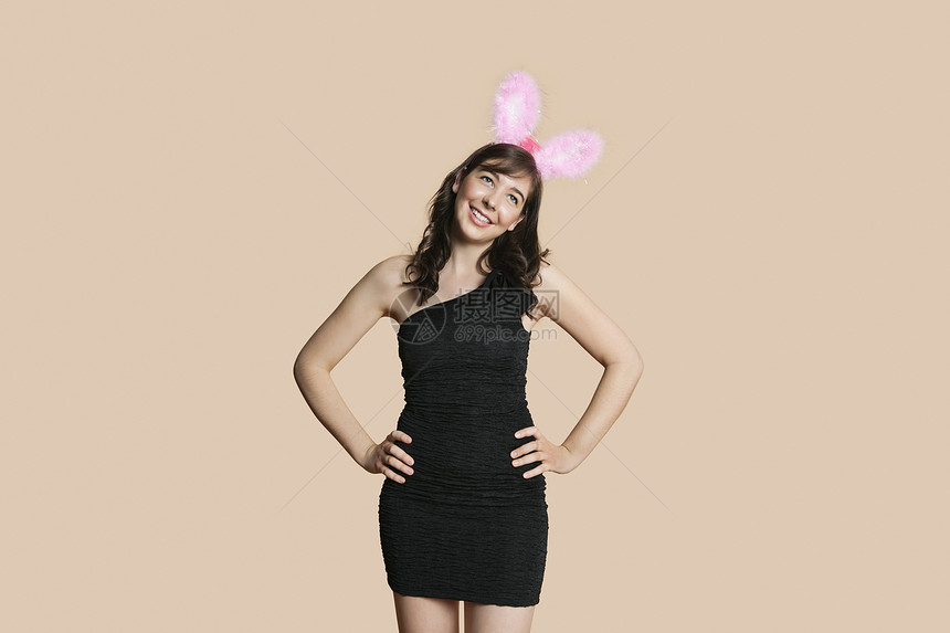 穿黑衣服的年轻美女 带着兔子耳朵 一边看着彩色背景边图片