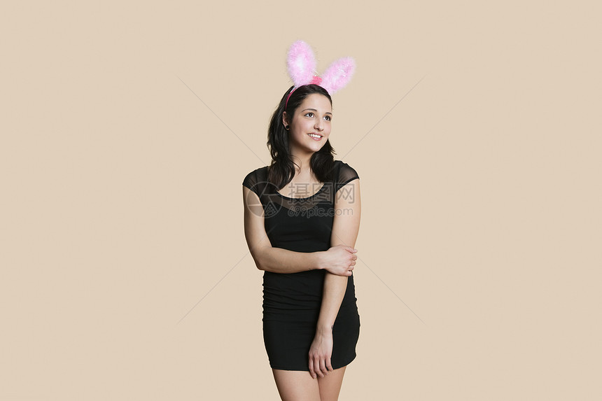 身穿兔子耳朵的快乐年轻女子 对彩色背景视而不见图片