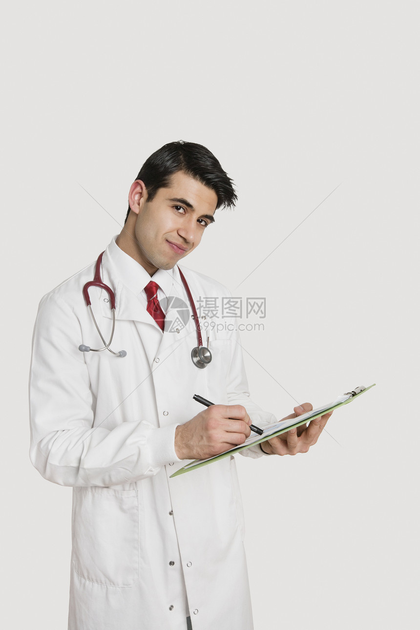 一名印度男医生在浅灰色背景上写处方的肖像图片