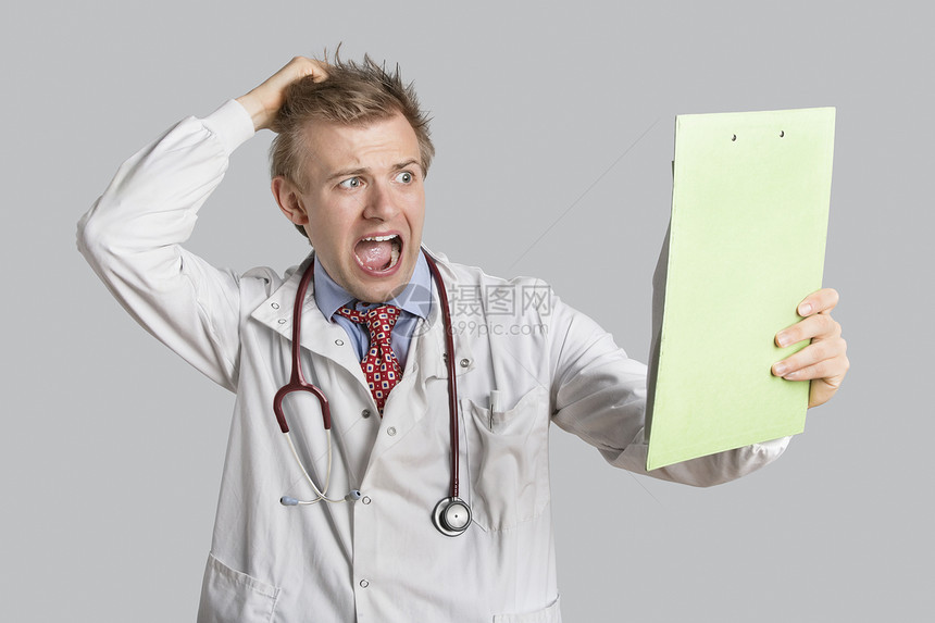 男性医生在看灰色背景的医疗报告时吓坏了男医生的眼神图片