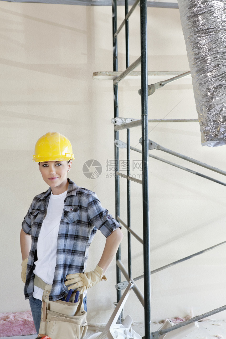 建筑工地中成年妇女手摸臀部的纵向肖像;图片