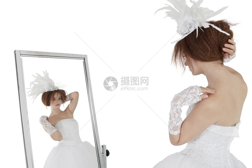 穿着婚纱的年轻黑发新娘 在白色背景上照着镜子看着自己图片