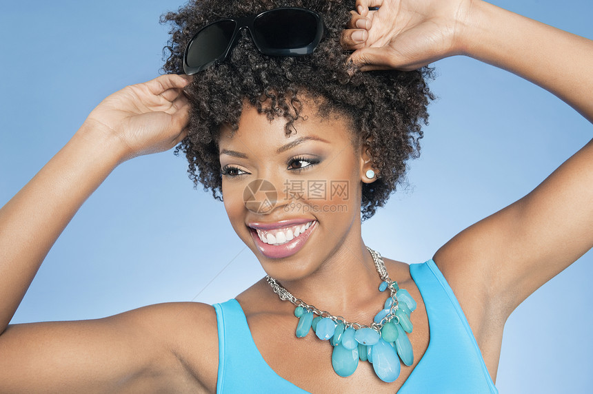 快乐的非洲裔美国女人调整太阳镜 而忽视彩色背景 (笑声)图片