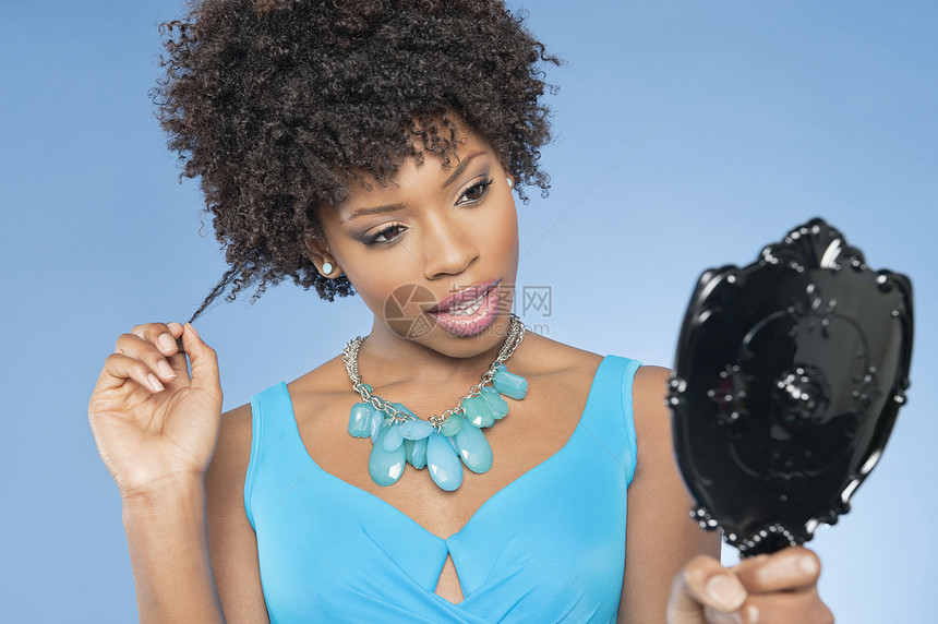 迷人的非裔美国女人 在彩色背景上照着镜子看自己的身影图片