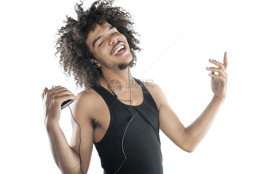 一位快乐的年轻男子在白色背景下聆听 mp3 播放器时垂手旁观的肖像图片