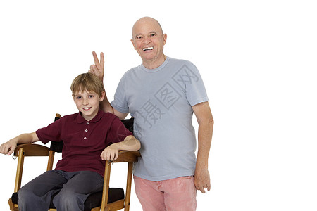 白色背景下坐在导演椅上的老人打着和平手势的画像背景图片