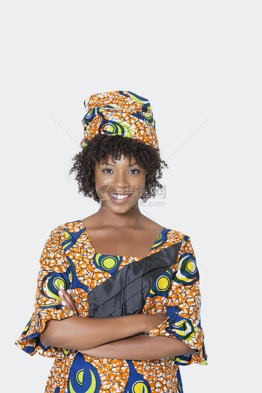 身着非洲印刷服装的年轻女性穿过灰色背景的双臂 肩膀交叉穿过灰色背景图片