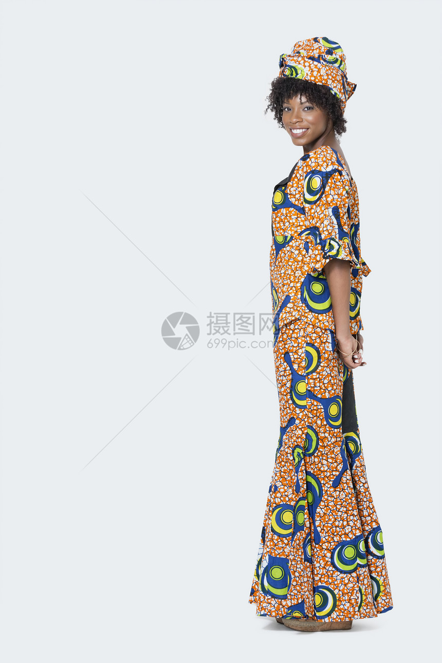 在灰色背景上站立的非洲印刷服装中 女青年全长肖像图片