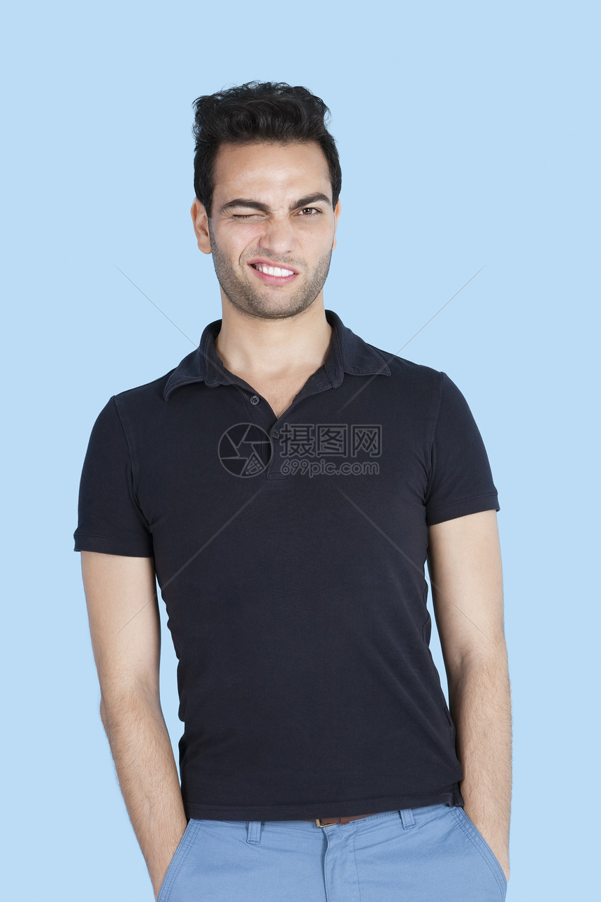 中年男子的肖像 用手在蓝背景上摸着口袋图片