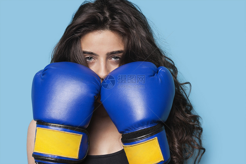 一个年轻女性拳手的肖像 蓝背景下拳头高举一拳图片