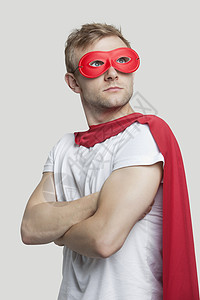穿着彩色超级英雄穿着红色超级英雄服装的年轻人 仰望着灰色背景背景