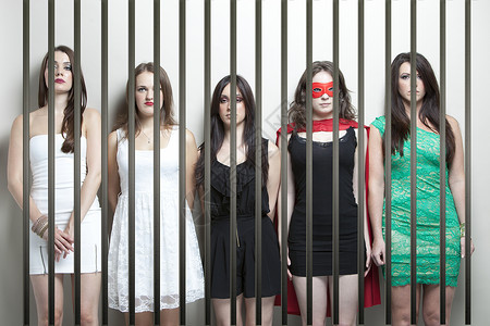 穿着超级英雄装扮的女人 和女朋友站在监狱牢狱后面面具眼罩成人裙子刑事五个人团结女性惩罚戏服背景
