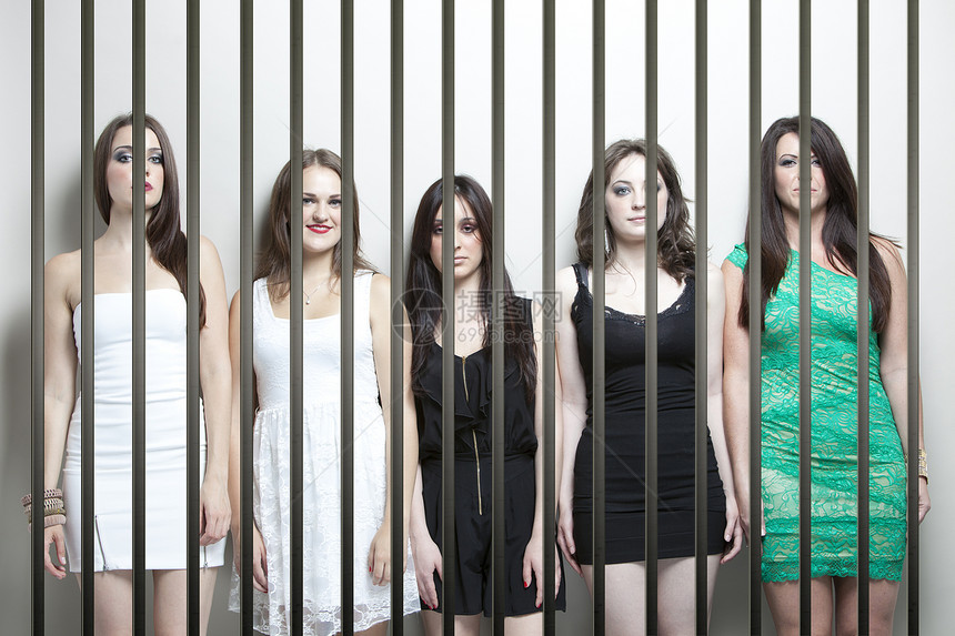 5名女青年站在监狱牢房后面并肩站立的肖像图片
