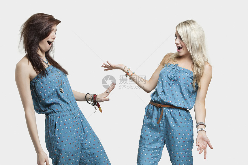 两个穿着相似的跳身服的女人 以灰色的背景互相看着对方 很惊讶图片