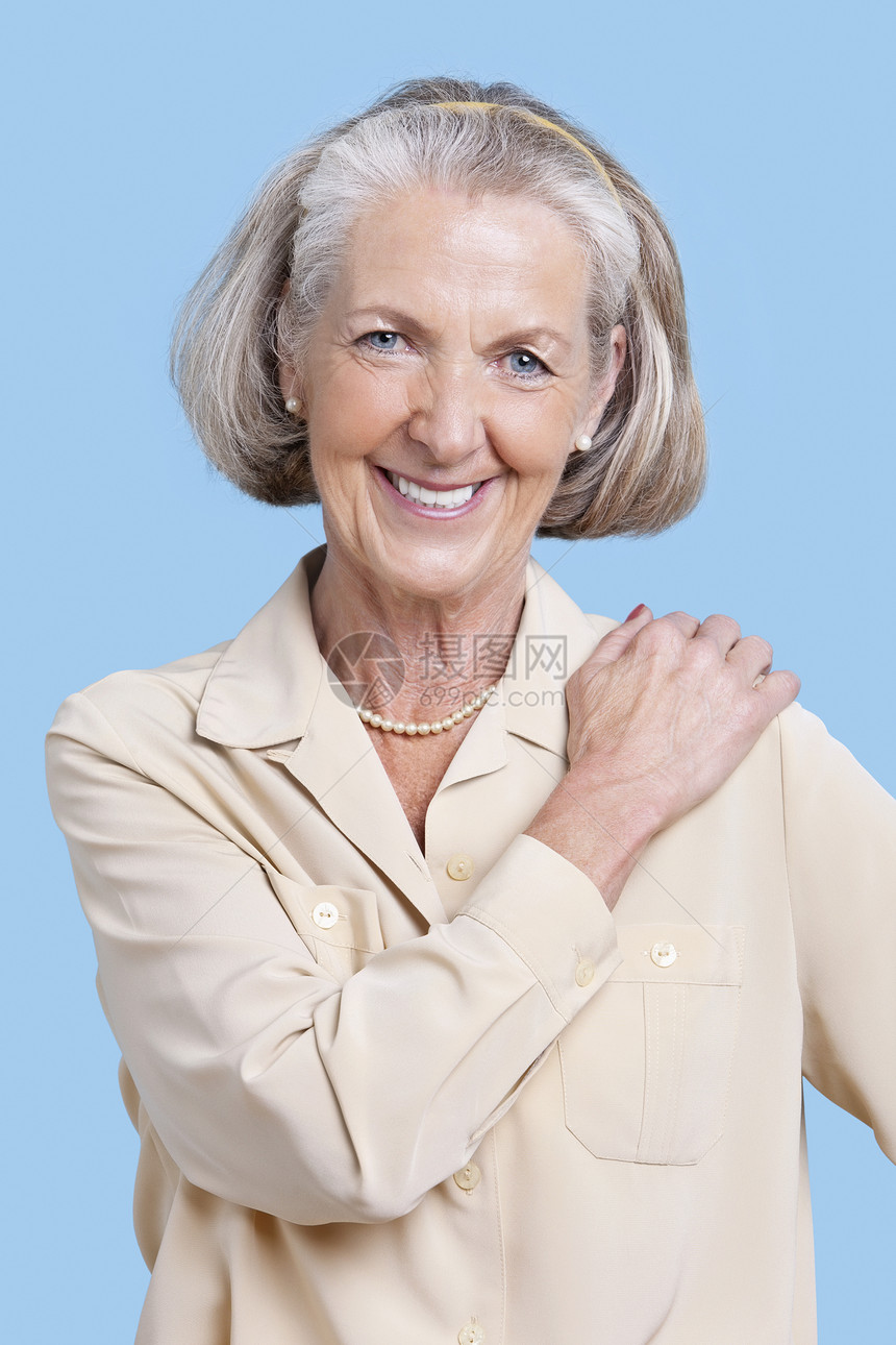 在蓝色背景下手肩膀搭靠着手的零食中 微笑着笑容的高级妇女肖像图片