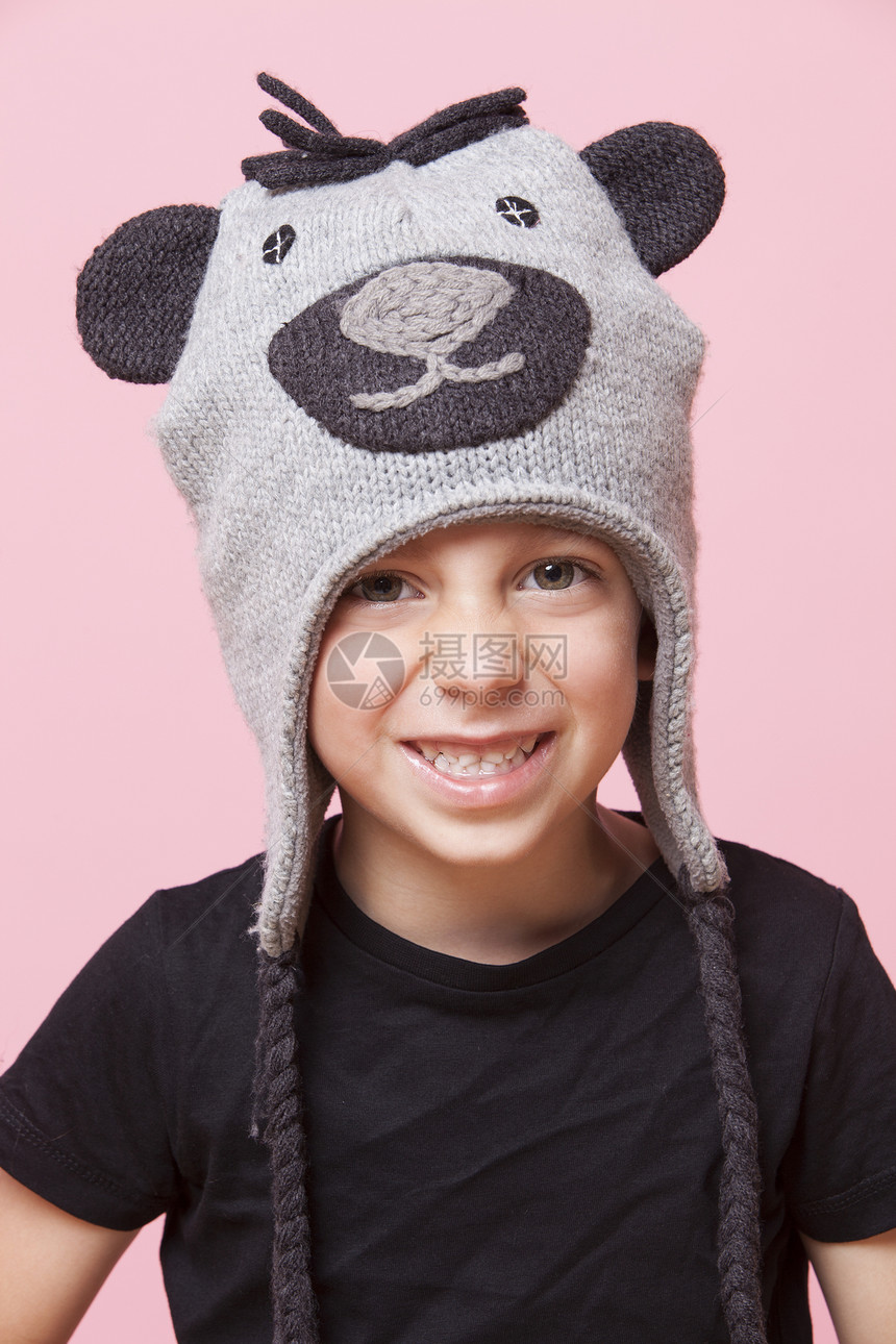一个快乐的年轻男孩的肖像 身戴猴子帽 背着粉红背景帽子青年影棚男生孩子童年男性休闲小学针织帽图片
