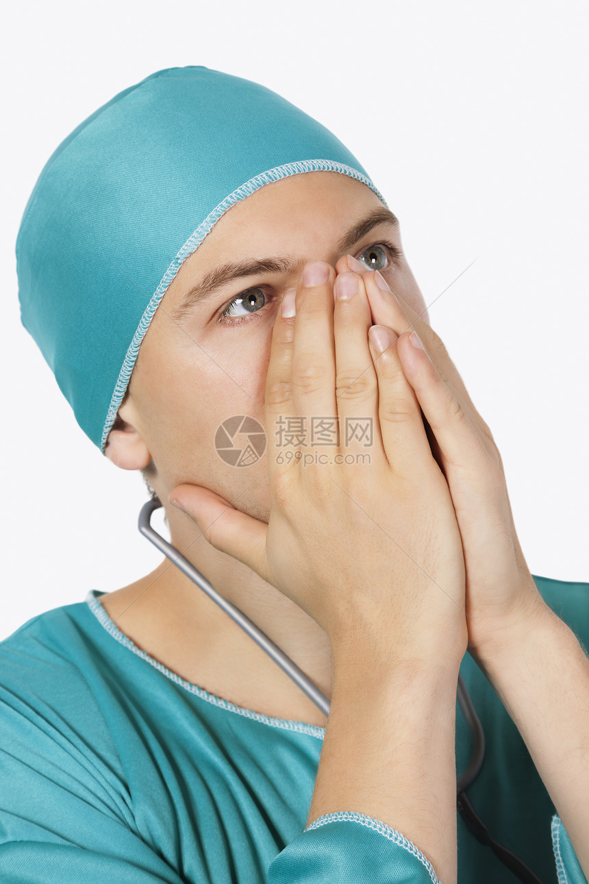 一名男性外科医生 在白色背景下用洗涤剂向上看 心烦意乱的男性外科医生图片