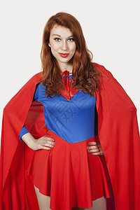 穿着彩色超级英雄穿着超级英雄服装的年轻女性肖像 在灰色背景下手握臀部背景
