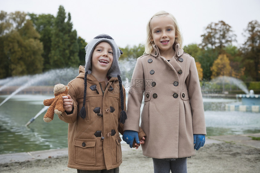 身穿在公园握手的战壕大衣 兄弟姊妹快乐的肖像图片