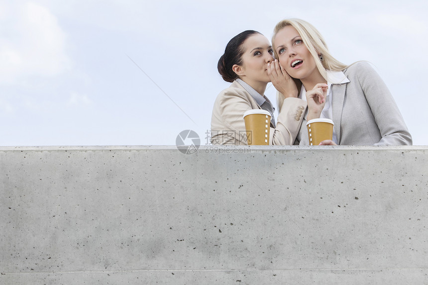 商业女商务人士的低角度视角 在同事耳边低语时 站在阳台对天图片