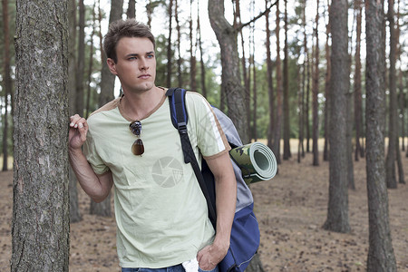 英俊的年轻人 背着背包在树林中徒步高清图片
