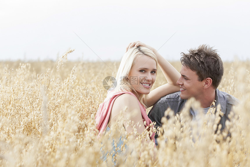 美丽的年轻女人的肖像 和男朋友一起坐在田野里图片