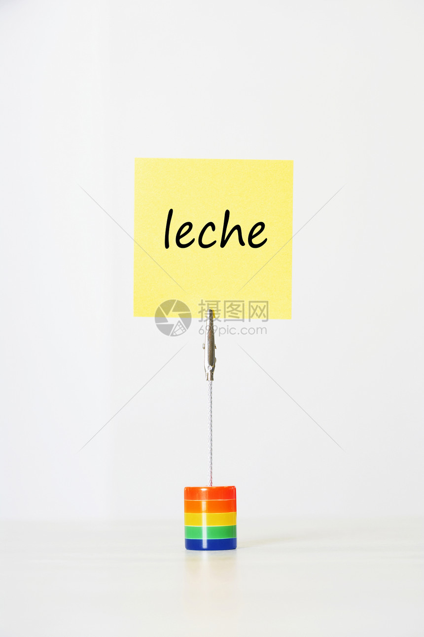 带有西班牙文文本“leche”(分子)的粘贴笔记纸 剪到多色卡持有人手中图片