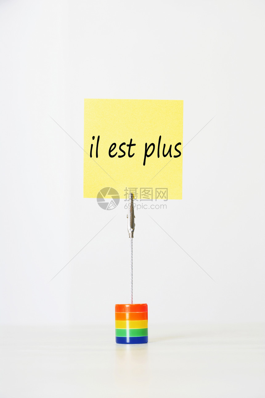 带有法文文本“in est+”(它已经结束)的粘贴纸纸 被剪到多色卡持有者手中图片