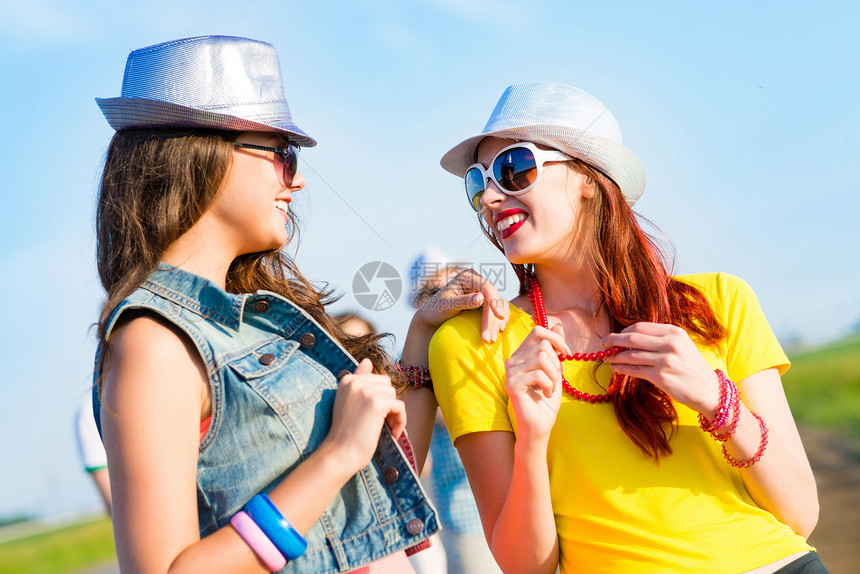 两个年轻女友玩得开心闲暇女性帽子乐趣晴天友谊派对幸福团体蓝色图片