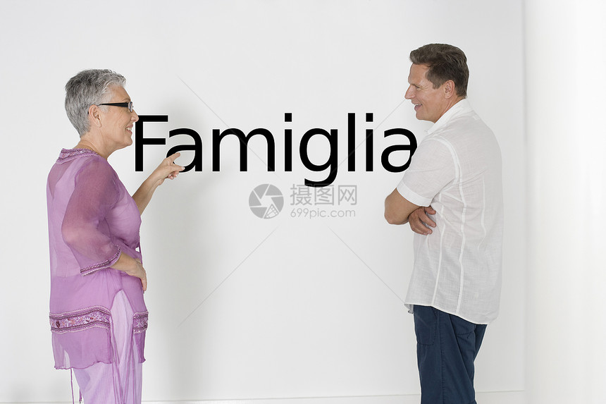 讨论家庭问题对抗白墙的一对夫妇与意大利文本“Famiglia”图片