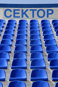 蓝色的空塑料体育场椅子 上面写着背景图片