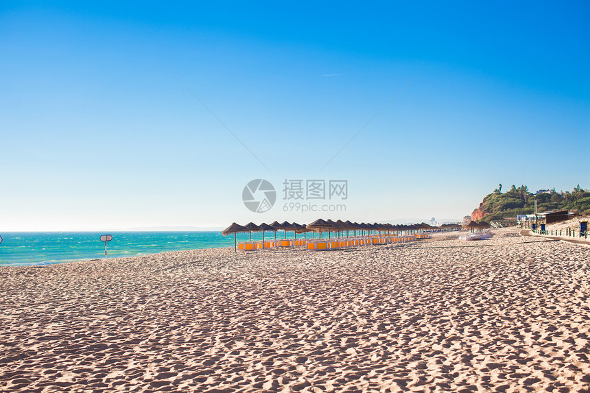 清晨在葡萄牙海岸的空沙滩上 有封闭的雨伞闲暇天堂躺椅海岸线旅游风景情调椅子日落旅行图片