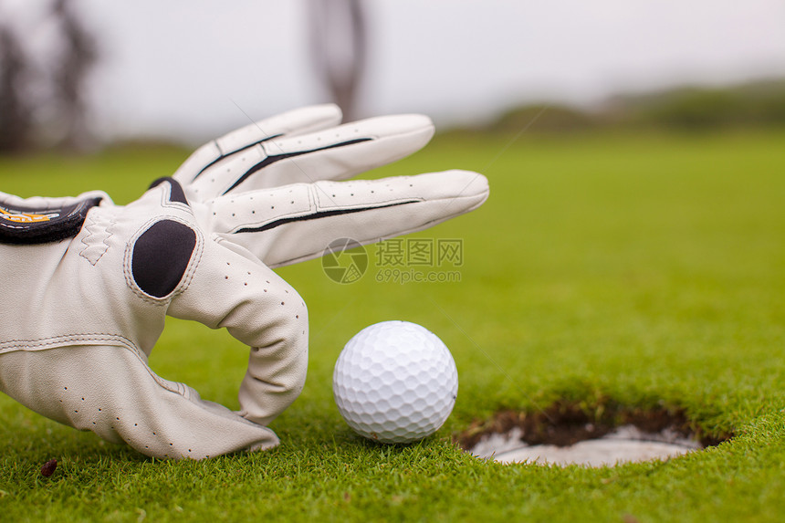 高尔夫球运动员把高尔夫球推进洞里手指推杆优胜者男性手套闲暇男人场地竞赛俱乐部图片