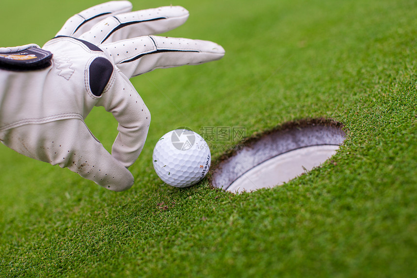 高尔夫球运动员把高尔夫球推进洞里场地裁剪推杆闲暇手套俱乐部游戏课程女性夫球图片