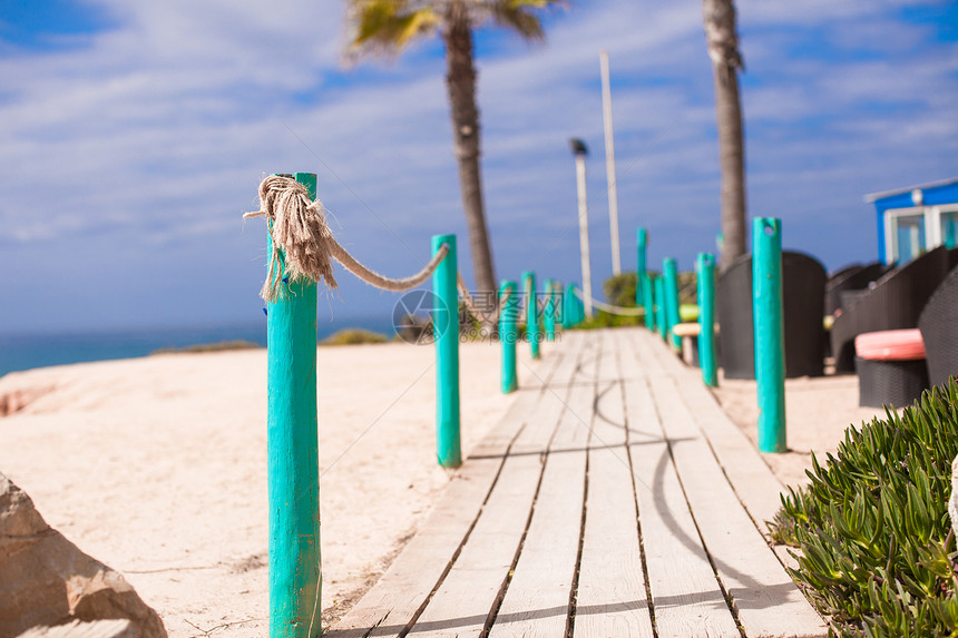 Wooden 走向沙沙滩的步行道甲板海浪行人蓝色天空棕榈海岸甜点小路游客图片