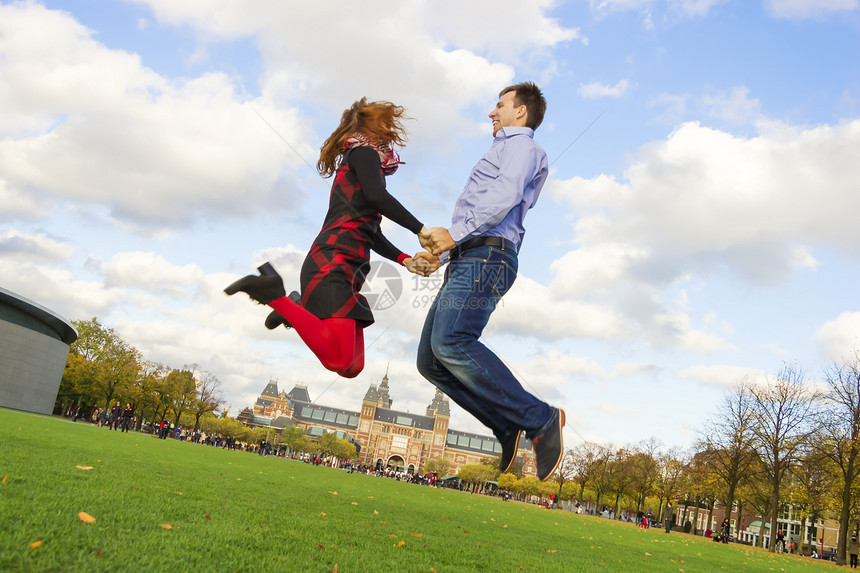 户外快乐的情侣在阿姆斯特丹博物馆城跳跃季节性男人拥抱广场夫妻博物馆享受季节微笑女士图片