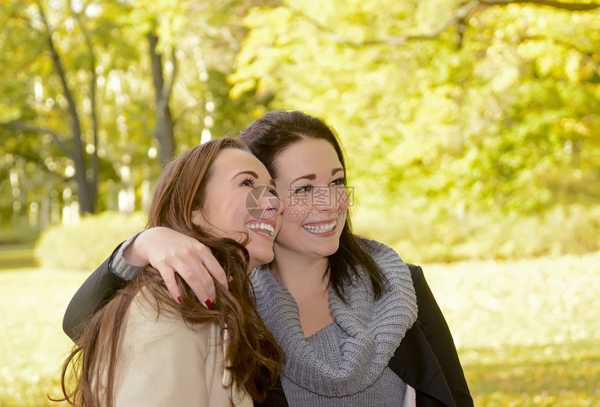 快乐的女朋友拥抱女子微笑树木公园运气兄弟姐妹姐姐感情青年图片