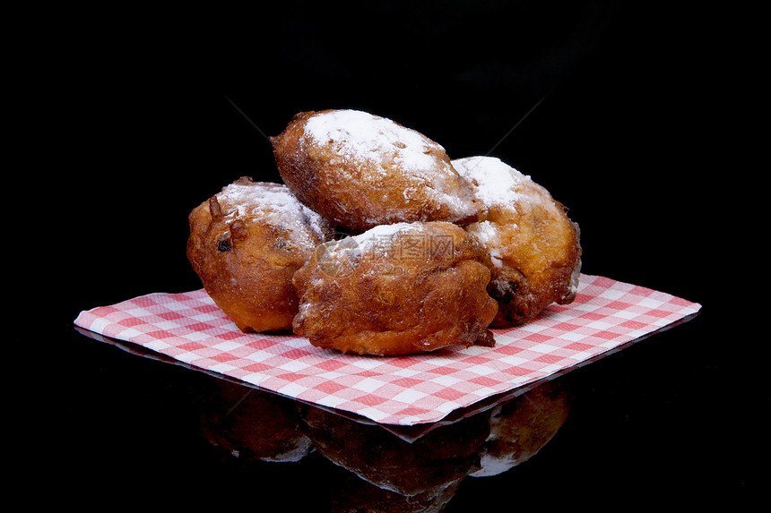荷兰甜甜甜圈又称奥利博伦 传统新叶葡萄干国家棕色背景育肥食物餐巾粉状黑色图片