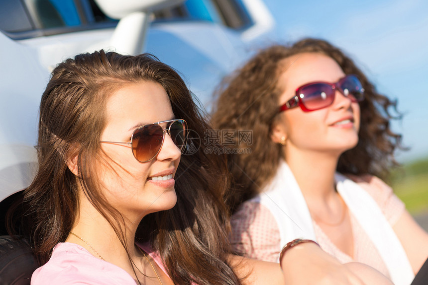 两名身戴墨镜的年轻美女树干车辆日落享受家庭天空情侣幸福女性男人图片
