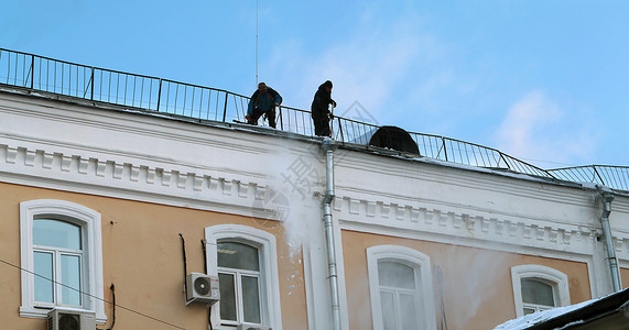 工人从屋顶净雪高清图片
